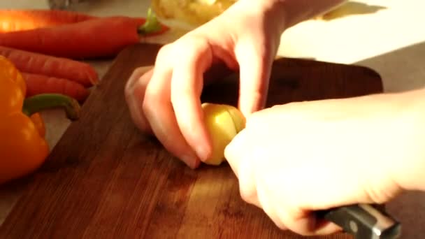 Su un tagliere di legno, il cuoco taglia i tuberi di patate crude con un coltello. Le mani femminili tengono un coltello affilato e dadi patate per minestra. — Video Stock