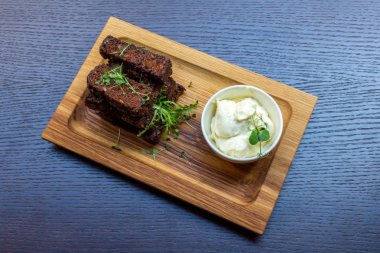 Siyah ahşap zemin üzerine beyaz soslu lezzetli kavrulmuş sarımsak ekmek kahverengi woodel tabağı tabak