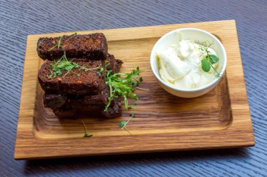 Siyah ahşap zemin üzerine beyaz soslu lezzetli kavrulmuş sarımsak ekmek kahverengi woodel tabağı tabak