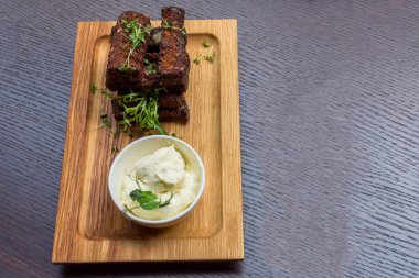 Siyah ahşap zemin üzerine beyaz soslu lezzetli kavrulmuş sarımsak ekmek kahverengi woodel tabağı tabak