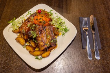 Kahverengi masa arka planda bir çatal ve bıçak ile domuz eti veya sığır Yağlı yağlı kaburga ve sebze ile beyaz çanak