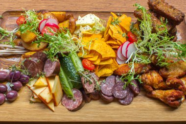 Aperatifler eti, tavuk budu, kahverengi ahşap tabakta sarımsak ekmek, sebze, turuncu ve beyaz sos çeşitleri