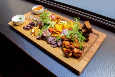 Aperatifler eti, tavuk budu, kahverengi ahşap tabakta sarımsak ekmek, sebze, turuncu ve beyaz sos çeşitleri