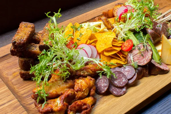 Aperatifler eti, tavuk budu, kahverengi ahşap tabakta sarımsak ekmek, sebze, turuncu ve beyaz sos çeşitleri