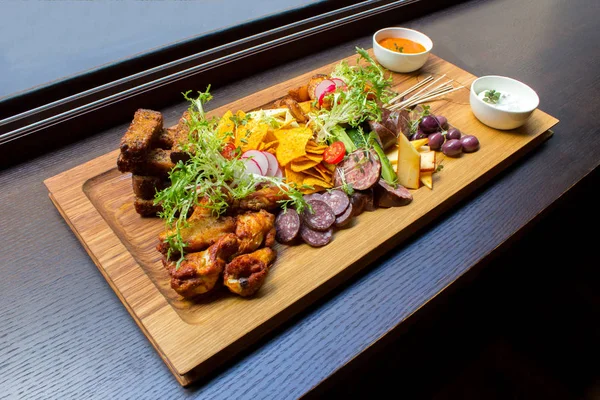 Ürün yelpazesine aperatifler eti, tavuk budu, sarımsak ekmek, sebze, turuncu ve siyah beyaz soslar üzerinde kahverengi ahşap tabakta tablo arka plan