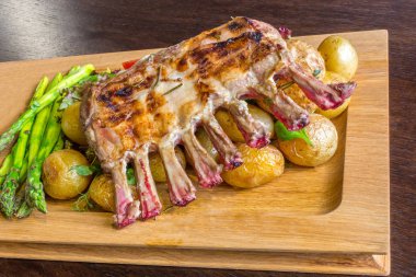 Lezzetli kuzu eti crown kızartma sebze salatası ve kahverengi ahşap masa ahşap tepside üzerinde kahverengi sos ile