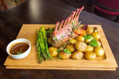 Lezzetli kuzu eti crown kızartma sebze salatası ve kahverengi ahşap masa ahşap tepside üzerinde kahverengi sos ile