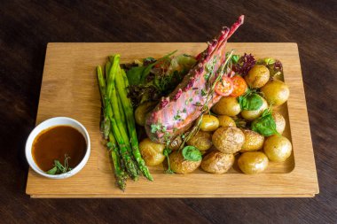 Lezzetli kuzu eti crown kızartma sebze salatası ve kahverengi ahşap masa ahşap tepside üzerinde kahverengi sos ile