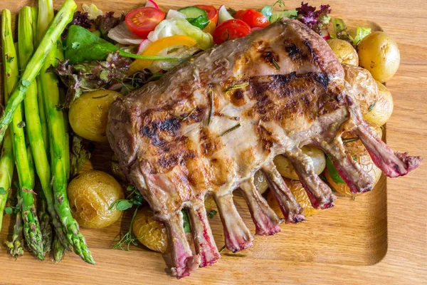 Lezzetli kuzu eti crown kızartma sebze salatası ve kahverengi ahşap masa ahşap tepside üzerinde kahverengi sos ile