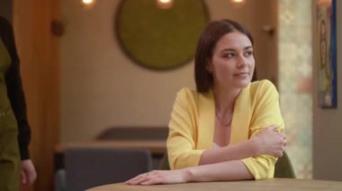 Bir garson kahvecideki bir kıza kahve getiriyor. Genç bir kadın güzel bir kafede lezzetli bir kahve bekliyor. Mutlu iş kızı lezzetli kahve içer..