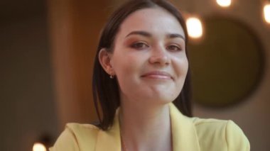 Bir kız kahve içiyor, mutlu genç bir kadın bir kafede oturuyor ve kahve içiyor. Karantinadan sonra bir kafe açmak.