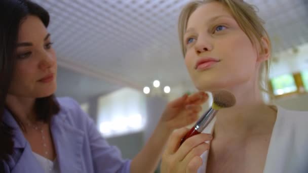 Make-up dívka klade make-up na blondýnu, dvě dívky dělat make-up, profesionální make-up umělec v procesu, profesionální make-up od brunetky — Stock video
