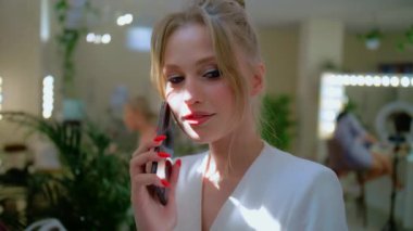 Şık bir sarışın telefonda konuşuyor, şık güzel bir kadın, mavi gözlü bir kız. Cep telefonuyla konuşurken gülümse.