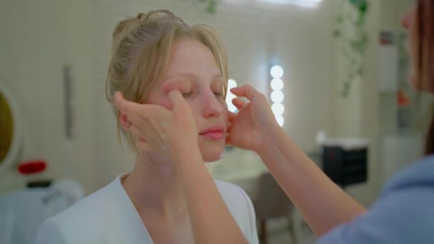Дівчина отримує косметичний масаж обличчя, масаж стресу для красивої блондинки — стокове відео