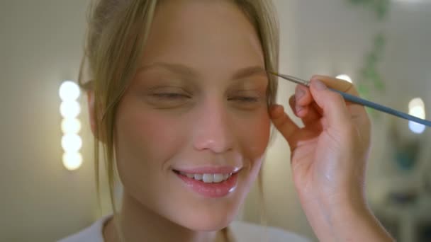 Seorang gadis pirang telah alisnya dicat, dan seorang wanita bahagia dengan mata biru telah datang ke spesialis makeup — Stok Video