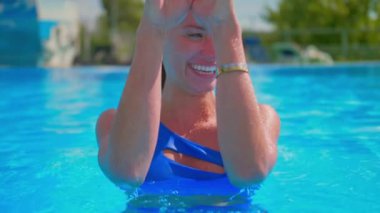 Mutlu sarışın kız havuzdan mavi suyu yavaş çekimde sıçrıyor ve gülüyor. .