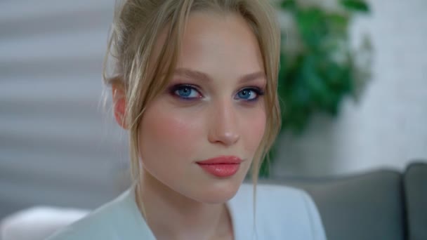 De blik van een meisje met make-up, een jonge vrouw die glimlacht en naar de camera kijkt, slow motion — Stockvideo