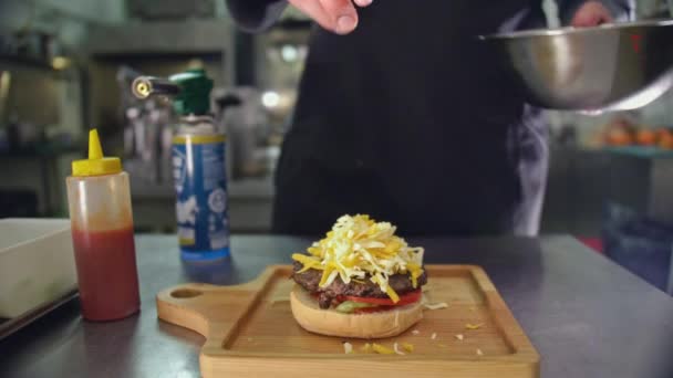Het koken van een cheeseburger, de Cook Stokes Parmezaanse kaas en cheddar met een gasbrander, moderne koken van een cheeseburger, de vlam van het vuur smelt de zachte kaas — Stockvideo