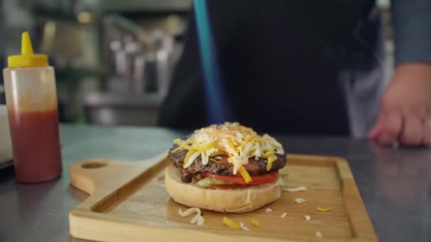 Het koken van een cheeseburger, de Cook Stokes Parmezaanse kaas en cheddar met een gasbrander, moderne koken van een cheeseburger, de vlam van het vuur smelt de zachte kaas — Stockvideo