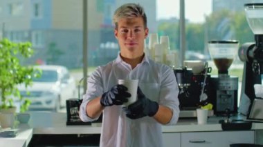 Barista Garson 'un portresi elinde bir fincan kahveyle bir kafede mutlu hissediyordu. Tişörtlü genç bir iş adamı kameraya bakarken dişlek bir gülümseme takınır.