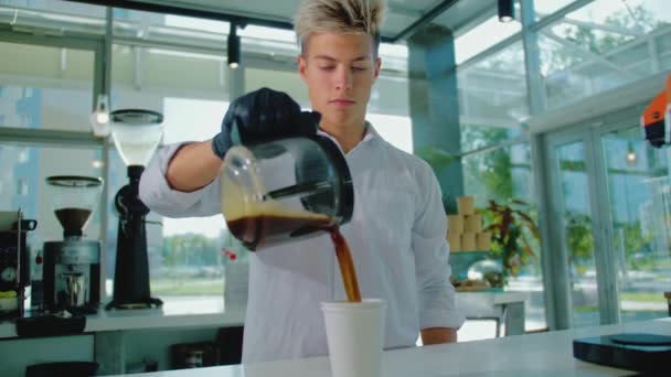 A Barista or waiter standing in a cafe and pouring coffee. A young employee works in the cafeteria. Concept of small business and public catering. Stock Video