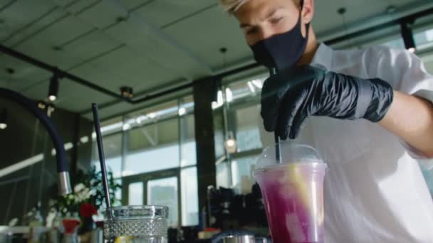 Un adolescent masqué travaillant dans un café prépare un cocktail à base de baies. Séquence Vidéo Libre De Droits
