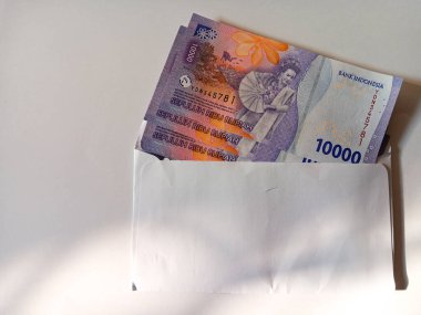 Stack of Indonesian money currency banknotes ten thousand rupiah inside a white envelope isolated on white background. Copy space for text.