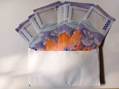 Stack of Indonesian money currency banknotes ten thousand rupiah inside a white envelope isolated on white background. Copy space for text.