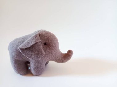 Doldurulmuş peluş, gri, küçük bir fil oyuncağı beyaz arka planda izole edilmiş. Metin için alanı kopyala.