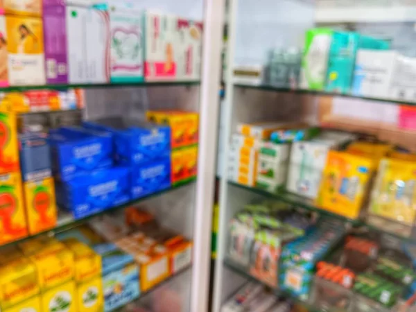 Blurred image of various packaged medications and healthcare products display on shelves in the pharmacy or medical store for defocused abstract background.