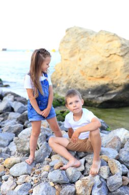 İki çocuk deniz kenarında kayalıklarda.