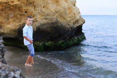 Güzel çocuk yazın deniz kıyısında durur.