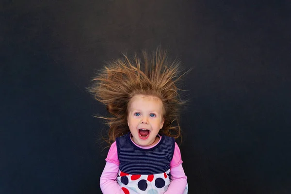 Portrait of a girl with electrified hair on a black background — Stock Photo, Image
