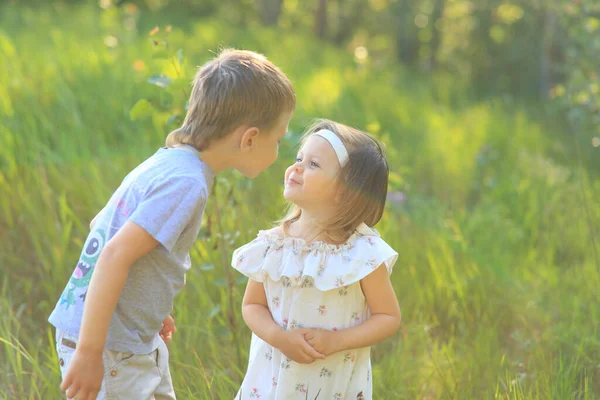 Liten pojke kramar en flicka på naturen på sommaren — Stockfoto