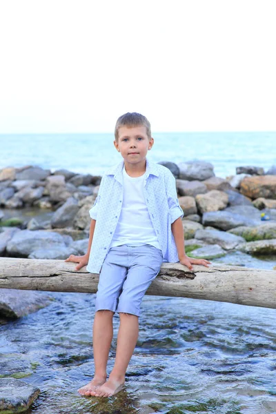 Egy gyermek a köveken a tenger közelében nyáron. — Stock Fotó