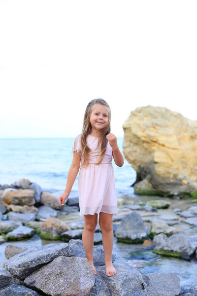 夏天，一个小孩在海边的石头上. — 图库照片