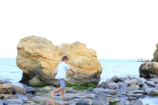 A child on the stones near the sea in summer. — Stock Photo, Image