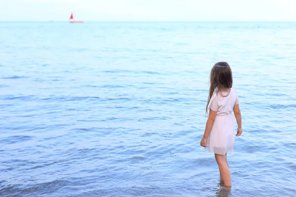 Cute girl stands on the seashore in summer — Stock Photo, Image