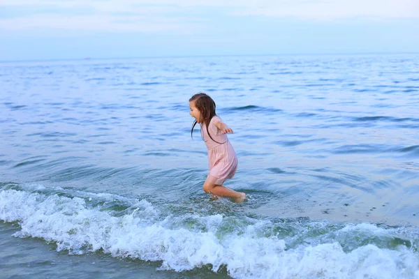 Un bambino scalzo cammina in riva al mare — Foto Stock