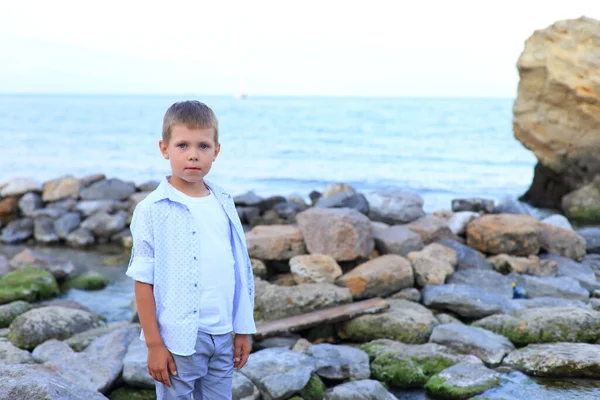 Un enfant sur les pierres près de la mer en été. — Photo