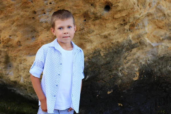 Un bambino sulle pietre vicino al mare in estate. — Foto Stock