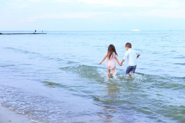 Zwei Kinder rennen in Küstennähe am Meer entlang — Stockfoto