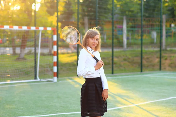 Девушка в школьной форме с ракеткой в руках на футбольном поле. — стоковое фото