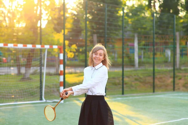 Девушка в школьной форме с ракеткой в руках на футбольном поле. — стоковое фото