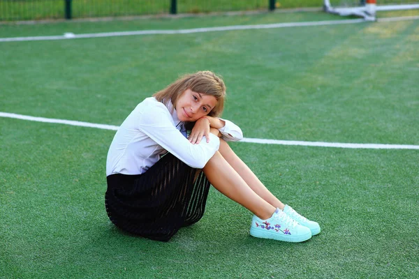 Ein Mädchen in Schuluniform mit einem Schläger in der Hand auf dem Fußballplatz. — Stockfoto