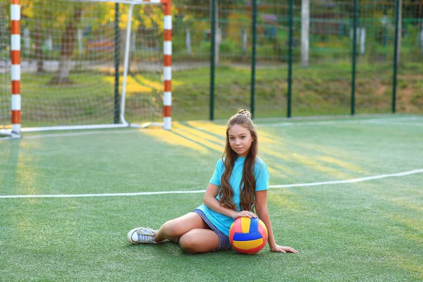 Menina com uma bola em suas mãos no campo de futebol . — Fotografia de Stock