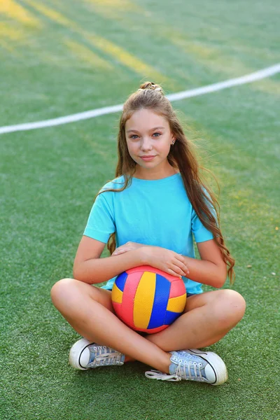 Menina com uma bola em suas mãos no campo de futebol . — Fotografia de Stock