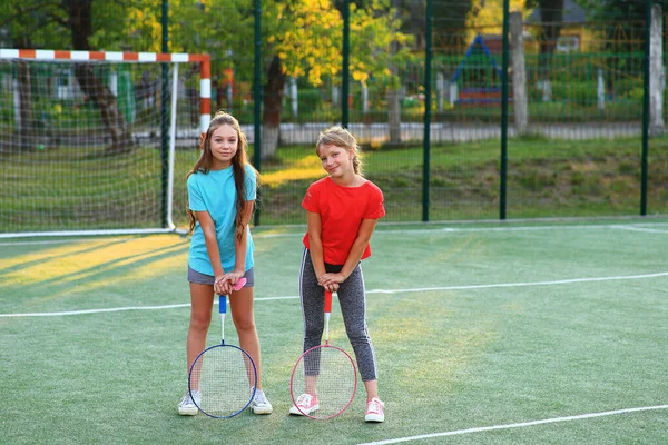 Dvě dívky s badmintonovými raketami na fotbalovém hřišti. — Stock fotografie
