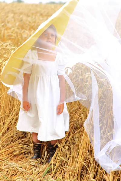 Dziecko w ogromnym żółtym kapeluszu w polu pszenicy latem — Zdjęcie stockowe