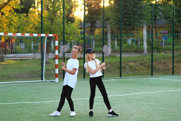 Dvě holky po vyučování jdou na tenis na hřišti. — Stock fotografie